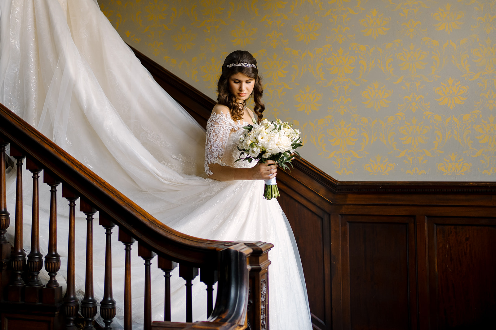 beautiful bride in white with bouquet on stairs